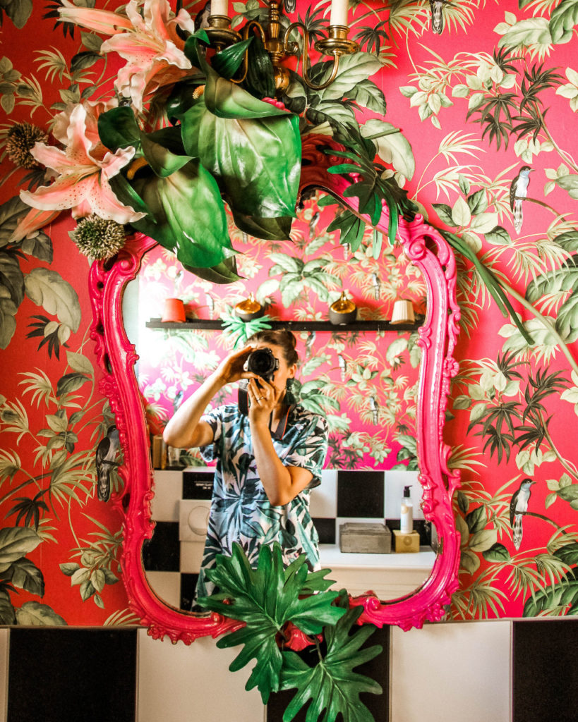 The vibrant pink and green wallpaper and mirror in the bathroom