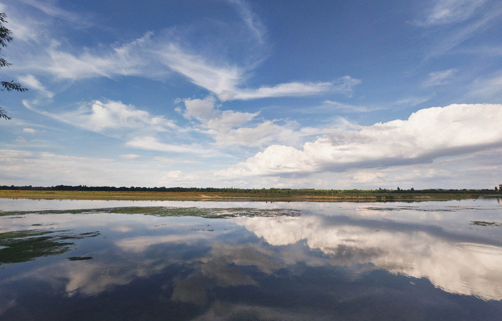 Port Meadow river with fluffy clouds in the sky and reflecting on the water