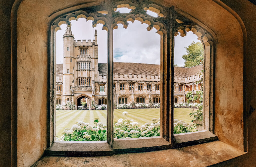 The old, stone building of Magdalen College as seen through a stone window