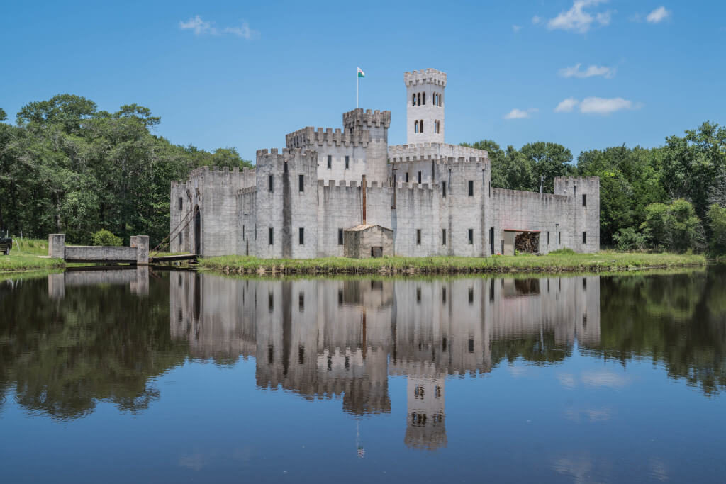 Medieval-looking castle with reflection in the moat surrounding it