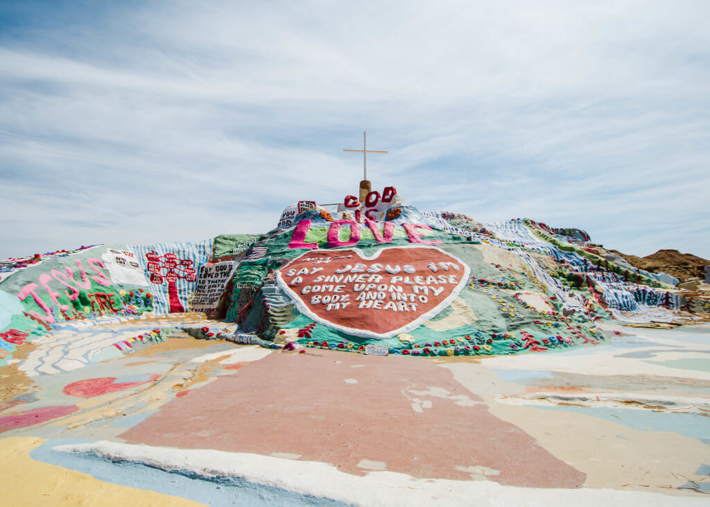 Front view of Salvation Mountain with brightly colored paint and Christian sayings written on it