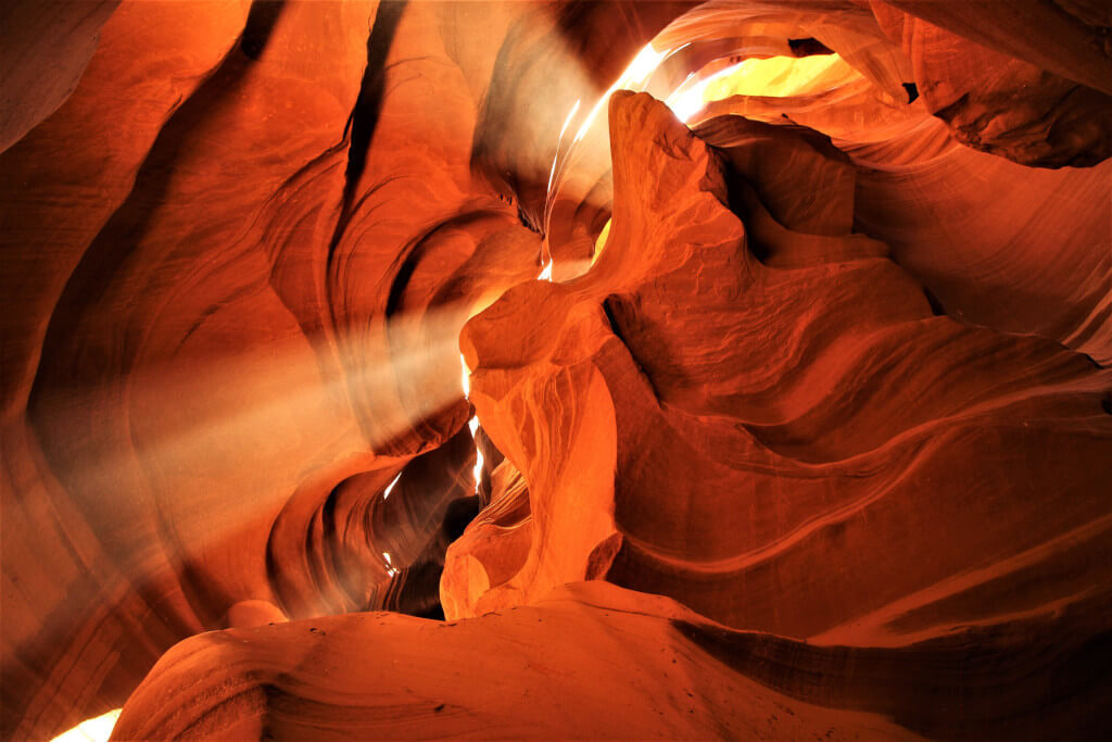 Beams of sunlight coming through the opening at the top of the slot canyon of Antelope Canyon